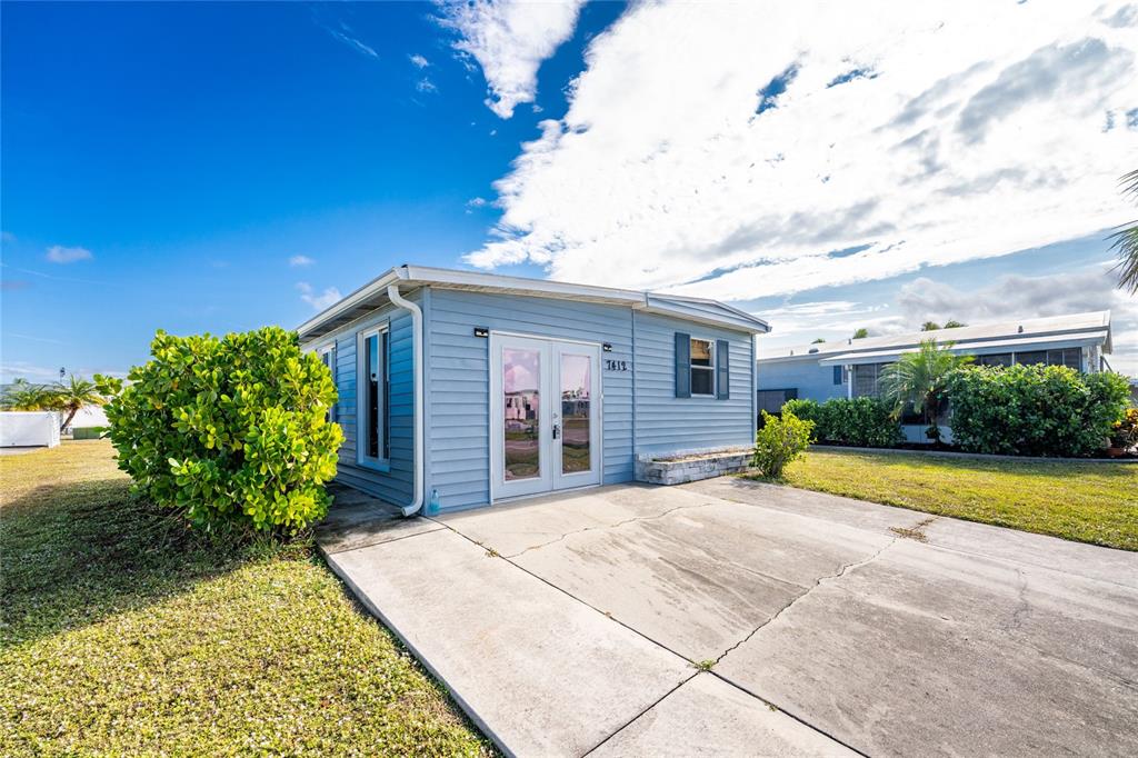 A light blue mobile home with a concrete driveway and a glass-paned front door — 7412 BECKLEY STREET, PORT CHARLOTTE, FL