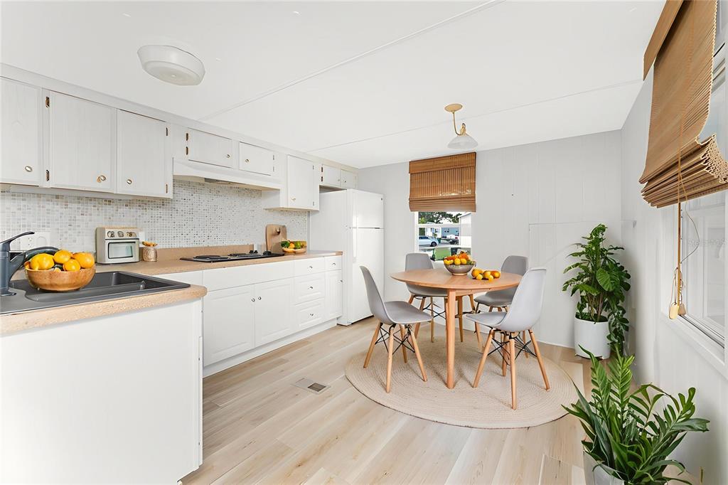 A kitchen and dining area with white cabinets, light wood flooring, and a round table — 7412 BECKLEY STREET, PORT CHARLOTTE, FL