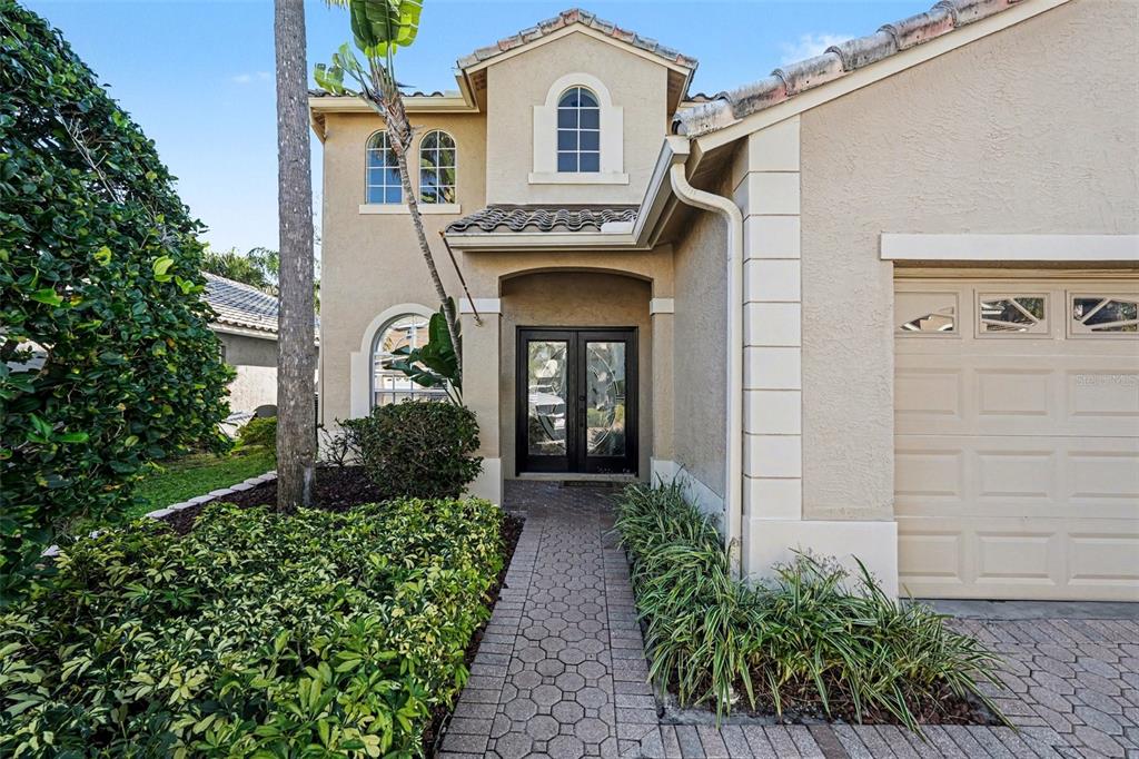 A beige house with a paved driveway, a two-car garage, and palm trees — 10618 HATTERAS DRIVE, TAMPA, FL