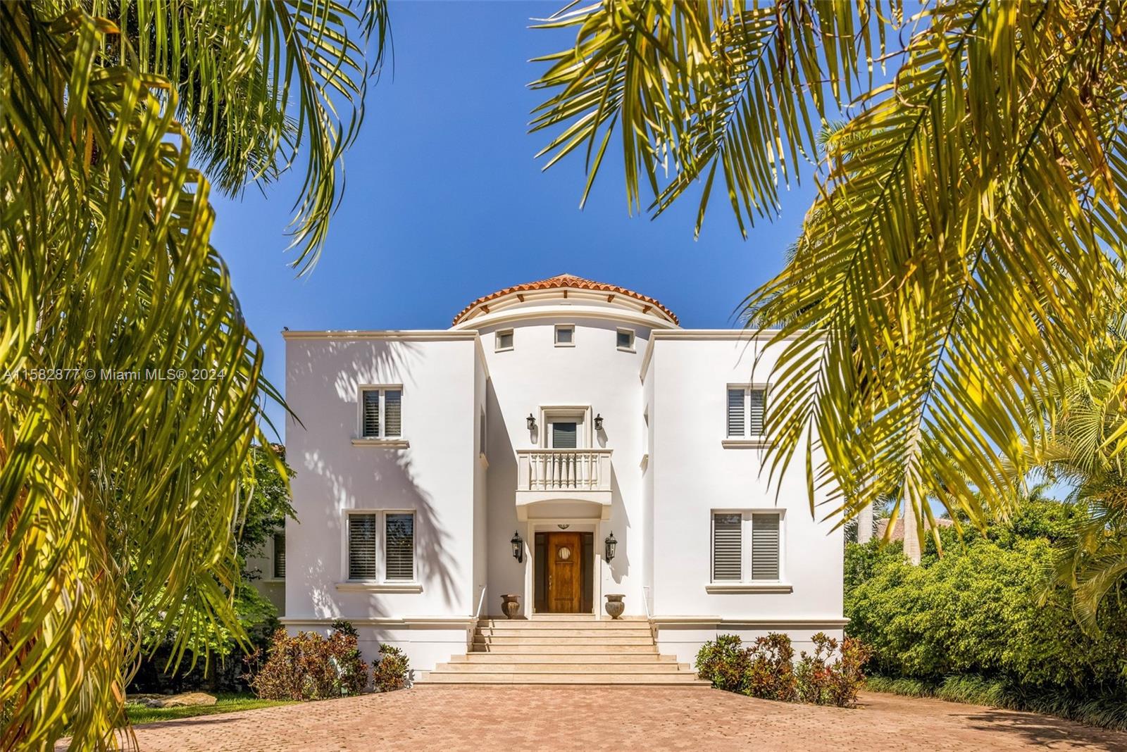 A white two-story Mediterranean-style house with a central balcony and palm trees in the foreground — 431 Costanera Rd, Coral Gables FL 33143, CORAL GABLES, FL
