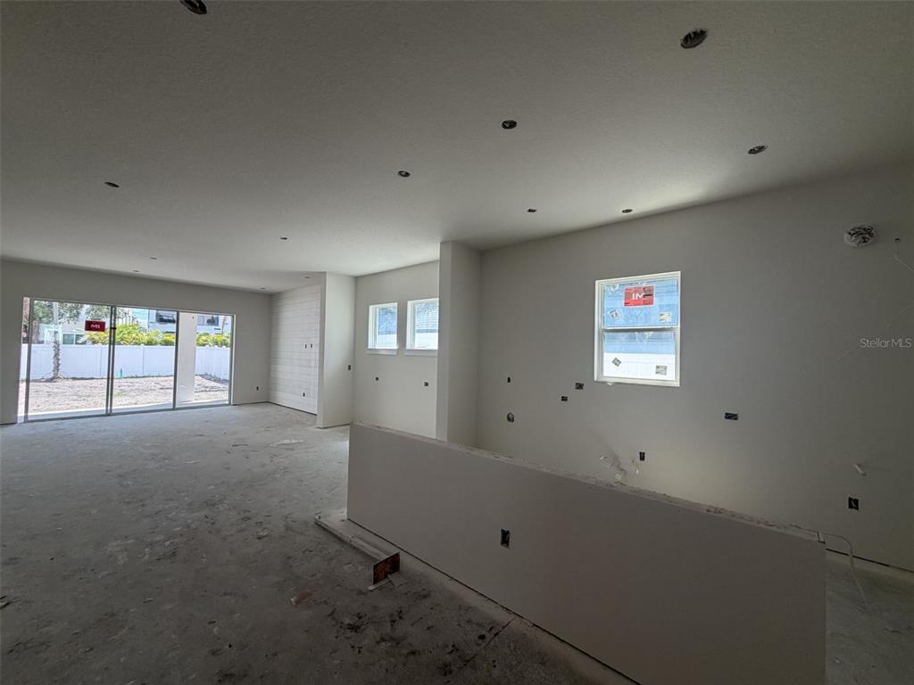 An unfinished room features white walls, recessed lighting, and large sliding glass doors — 1002 W CHARTER STREET, TAMPA, FL