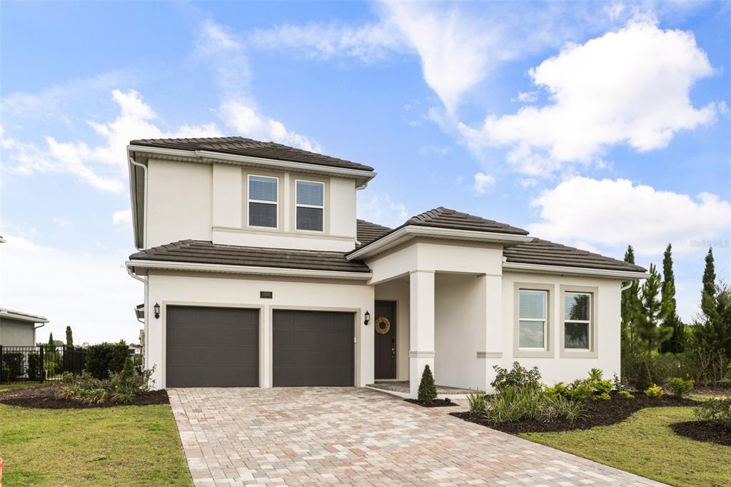A two-story house with a two-car garage, stucco exterior, and a paved driveway — 16000 VOLTERRA POINT, BELLA COLLINA, FL
