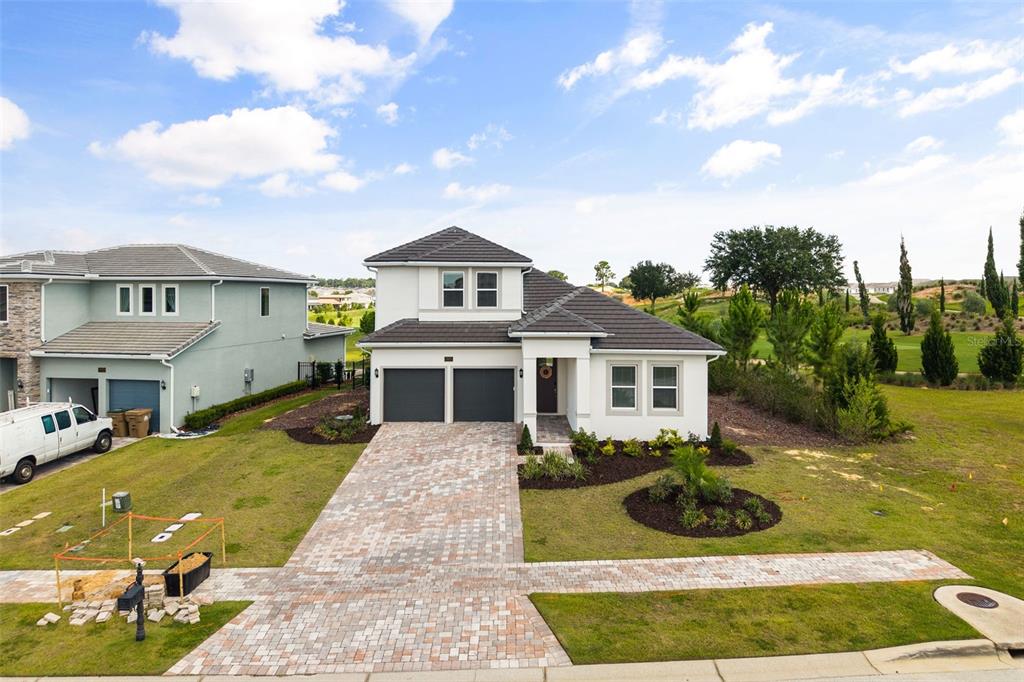 A two-story house with a paver driveway and a two-car garage sits on a lot — 16000 VOLTERRA POINT, BELLA COLLINA, FL