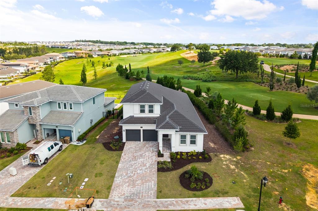 An aerial view shows a two-story house with a paver driveway overlooking a golf course — 16000 VOLTERRA POINT, BELLA COLLINA, FL