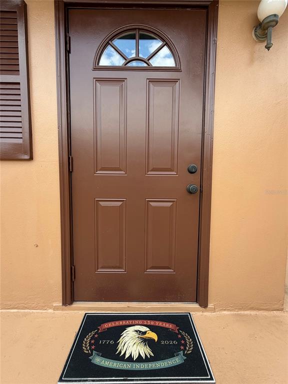 A brown front door with a semi-circular window sits above a patriotic welcome mat — 432 E STREET UNIT 432, CASSELBERRY, FL