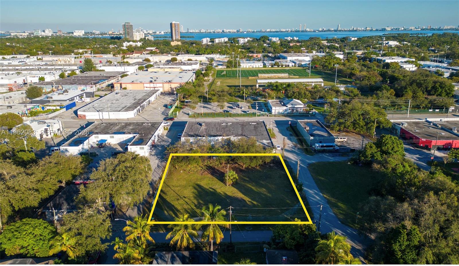 An aerial view shows a vacant, rectangular lot outlined in yellow near industrial buildings — 159 NE 64th St, Miami FL 33138, MIAMI, FL