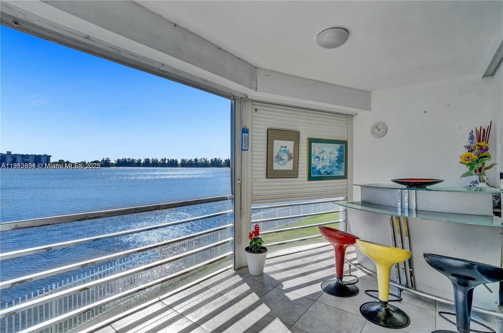 A balcony with a glass railing overlooks a large body of water — 1000 NE 191st St # 21, Miami FL 33179, MIAMI, FL