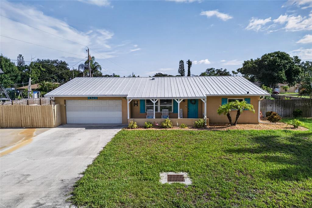 A single-story house with a metal roof, a garage, and a front porch with chairs — 895 E BAFFIN DRIVE, VENICE, FL