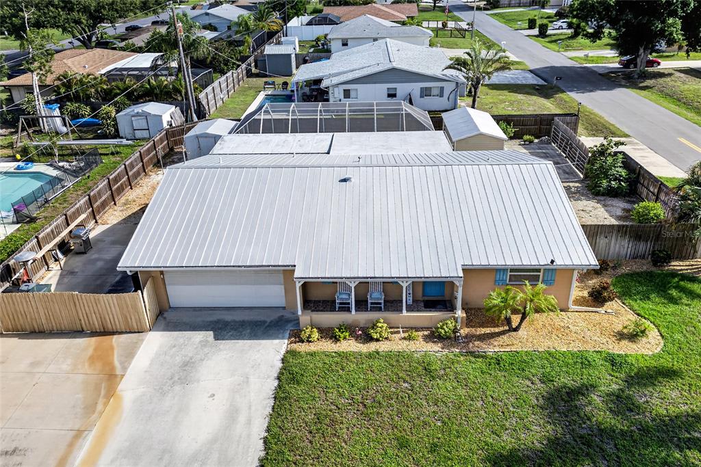 An aerial view of a single-story house with a metal roof and a front driveway — 895 E BAFFIN DRIVE, VENICE, FL