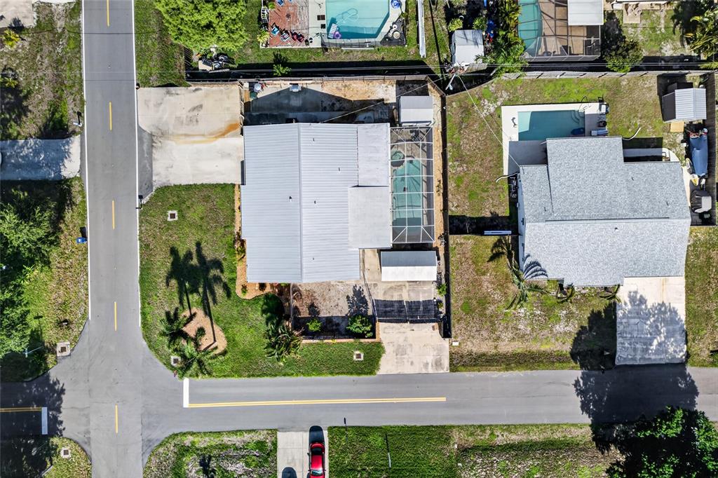 An aerial view shows two houses with swimming pools and screened enclosures on a residential street — 895 E BAFFIN DRIVE, VENICE, FL