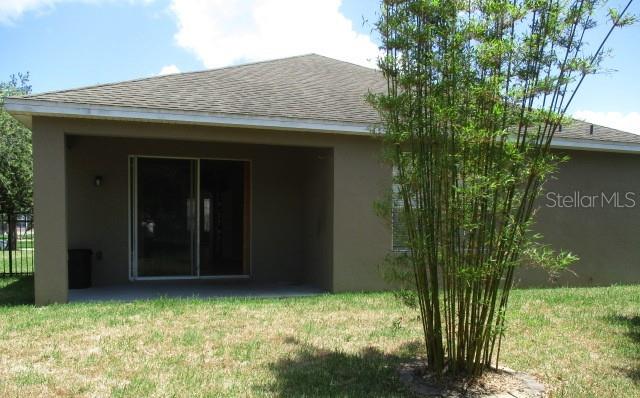 A view of a house exterior featuring a covered patio and a tall bamboo plant — 3827 SPIRITED CIRCLE, ST CLOUD, FL