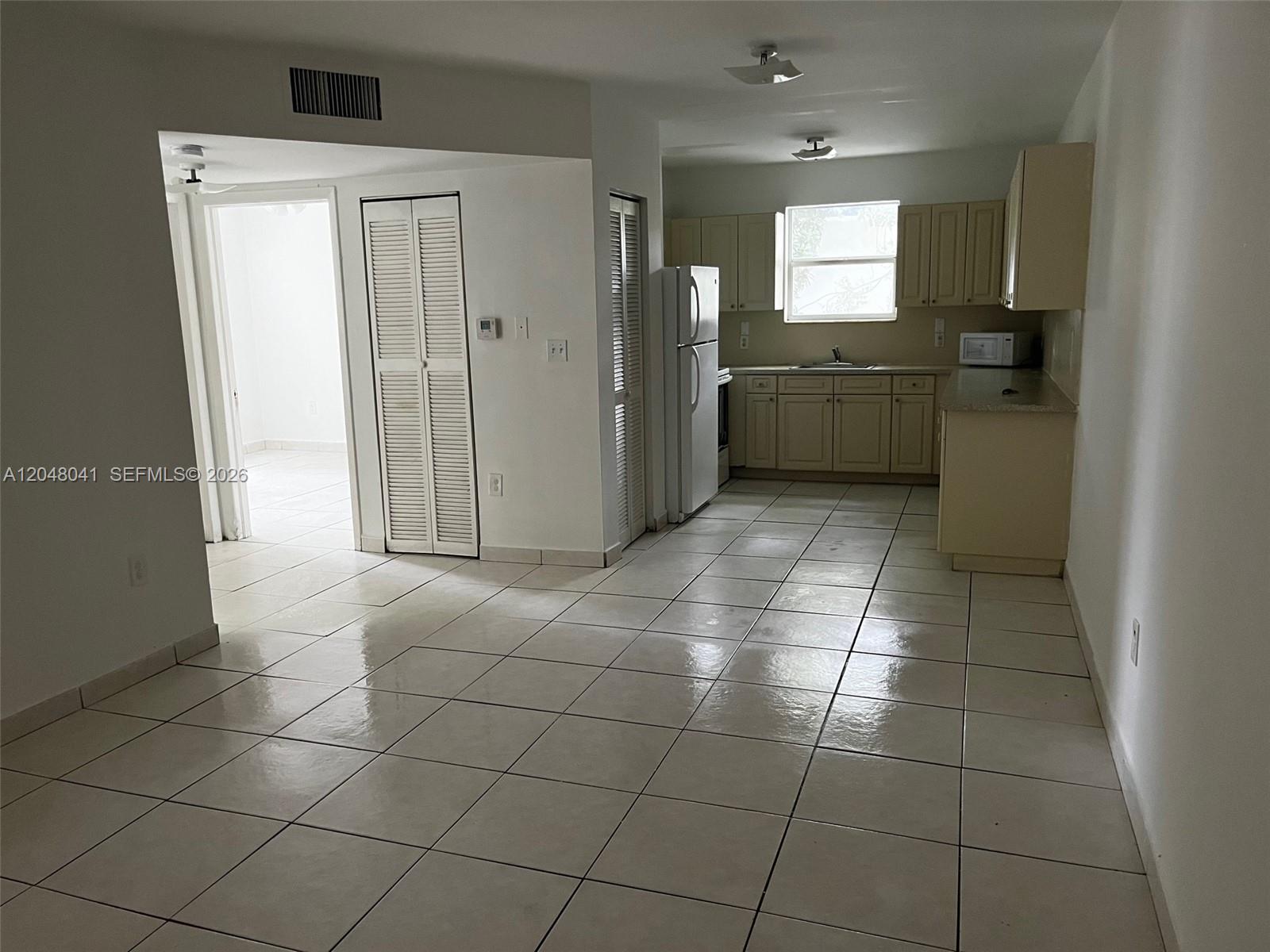 This kitchen features light-colored cabinets, white appliances, and tiled flooring in an open-concept space — 181 NW 47th Ave # 25, Miami FL 33126, MIAMI, FL