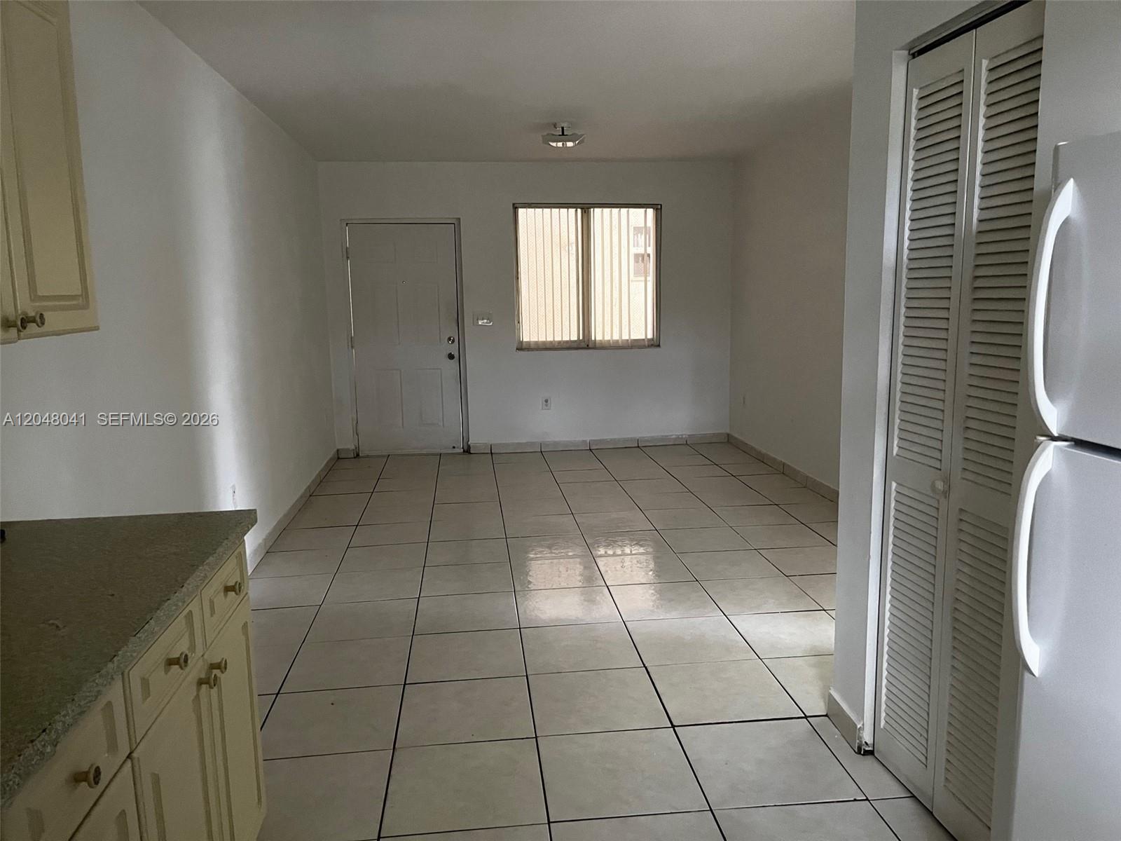 A kitchen area with tile flooring leads to an exterior door and a window — 181 NW 47th Ave # 25, Miami FL 33126, MIAMI, FL