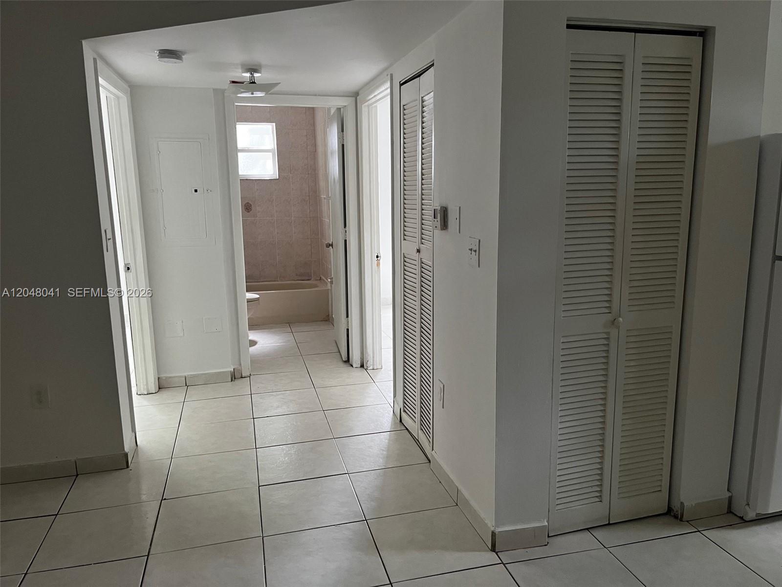 A hallway with white tiled floors leads to a bathroom with a bathtub — 181 NW 47th Ave # 25, Miami FL 33126, MIAMI, FL