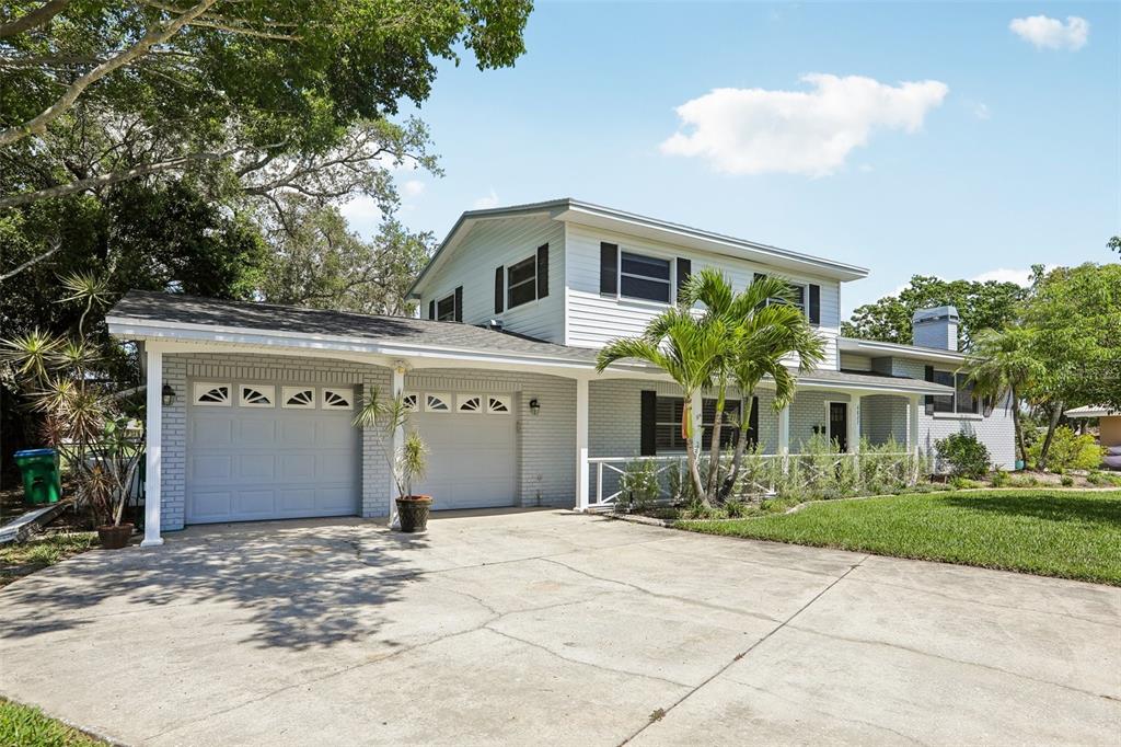 A two-story house with a light gray brick exterior, a two-car garage, and a palm tree — 6827 TEQUESTA DRIVE, SEMINOLE, FL