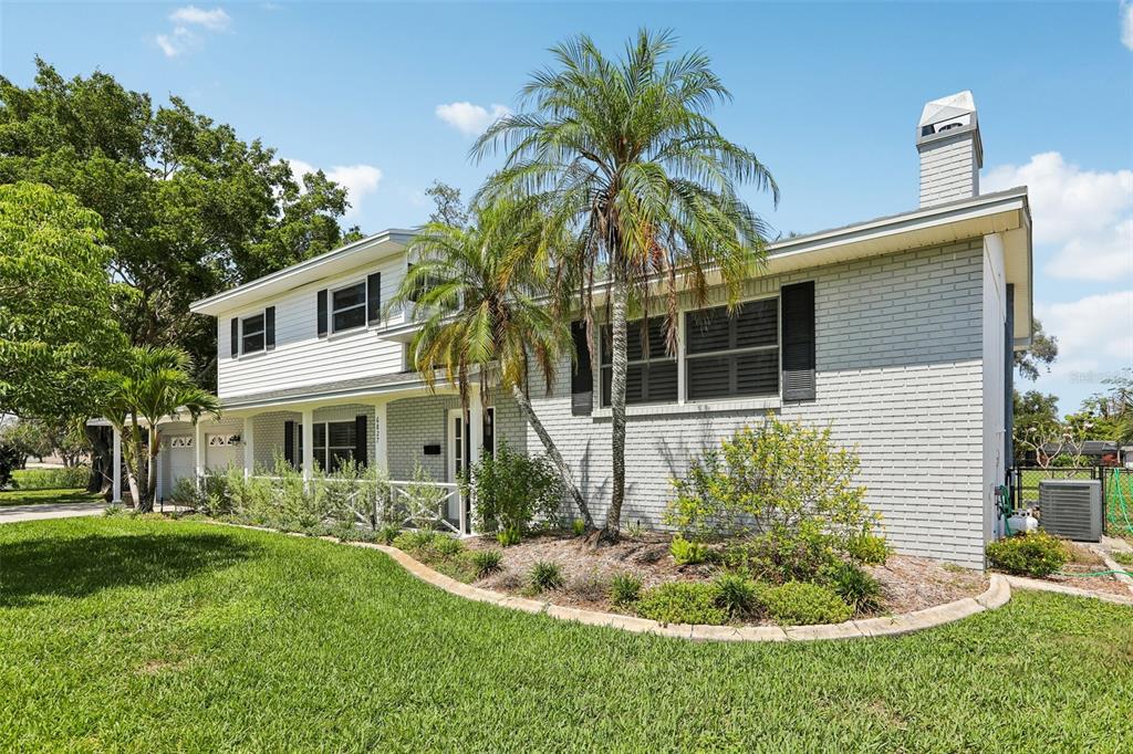 A two-story house with a light gray brick exterior, white siding, and a palm tree — 6827 TEQUESTA DRIVE, SEMINOLE, FL