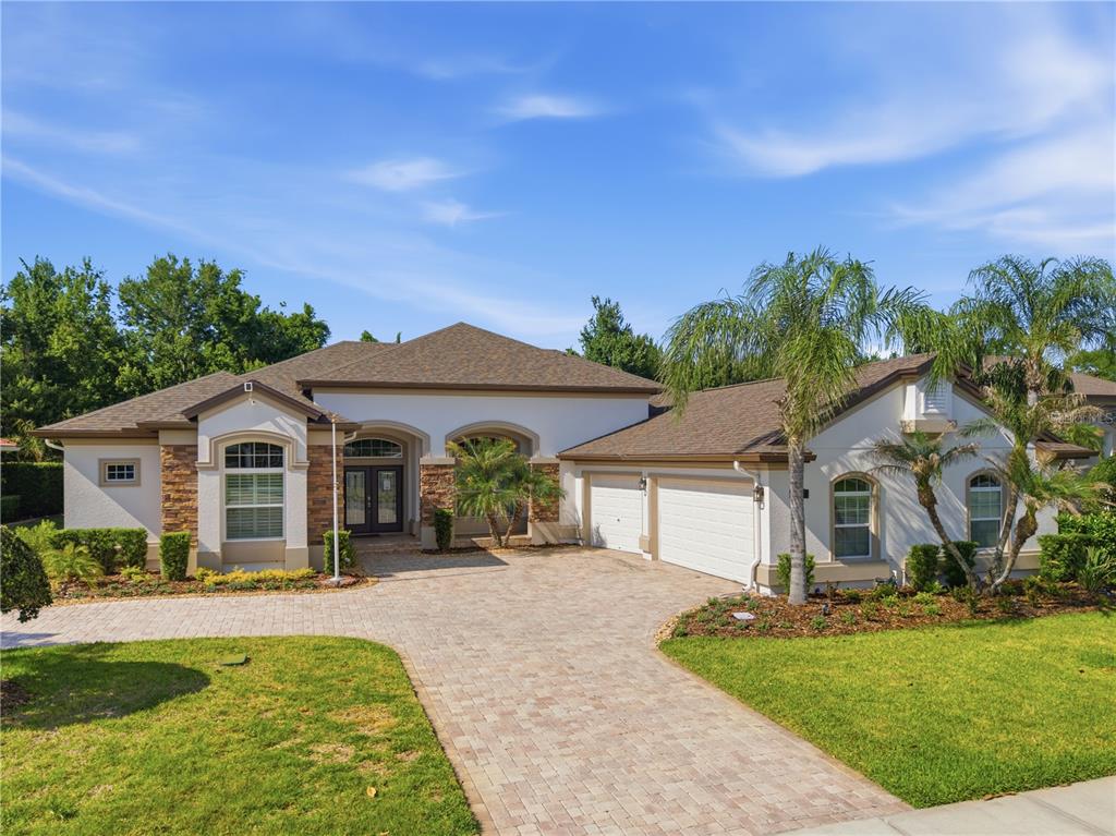 A single-story house with a paved driveway, three-car garage, and palm trees in the front yard — 8747 BONICA PLACE, LAND O LAKES, FL