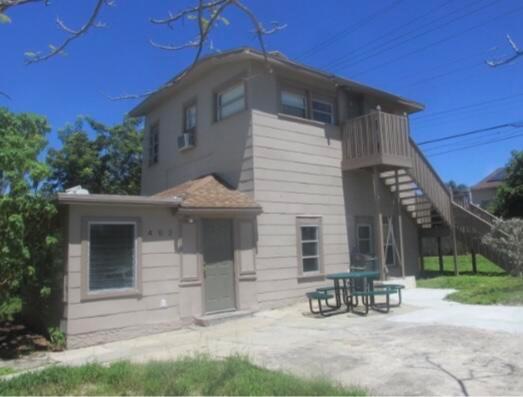 A two-story tan building with an exterior staircase and a picnic table on the patio — 402 N A Street, FL 33460, FL