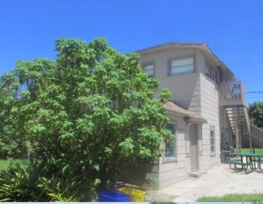 A two-story tan building with an exterior wooden staircase and a large green bush — 402 N A Street, FL 33460, FL