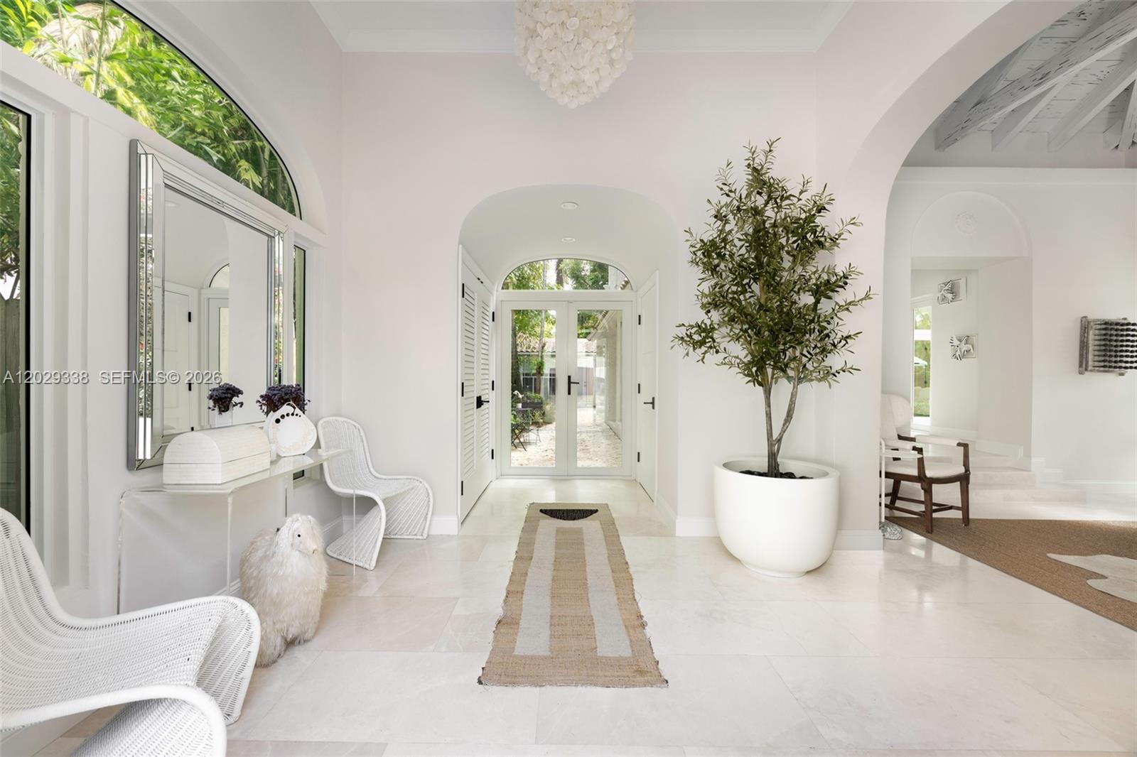 A bright, white-walled entryway features a tall potted tree, arched doorways, and light tile flooring — 3845 Wood Ave, Miami FL 33133, MIAMI, FL