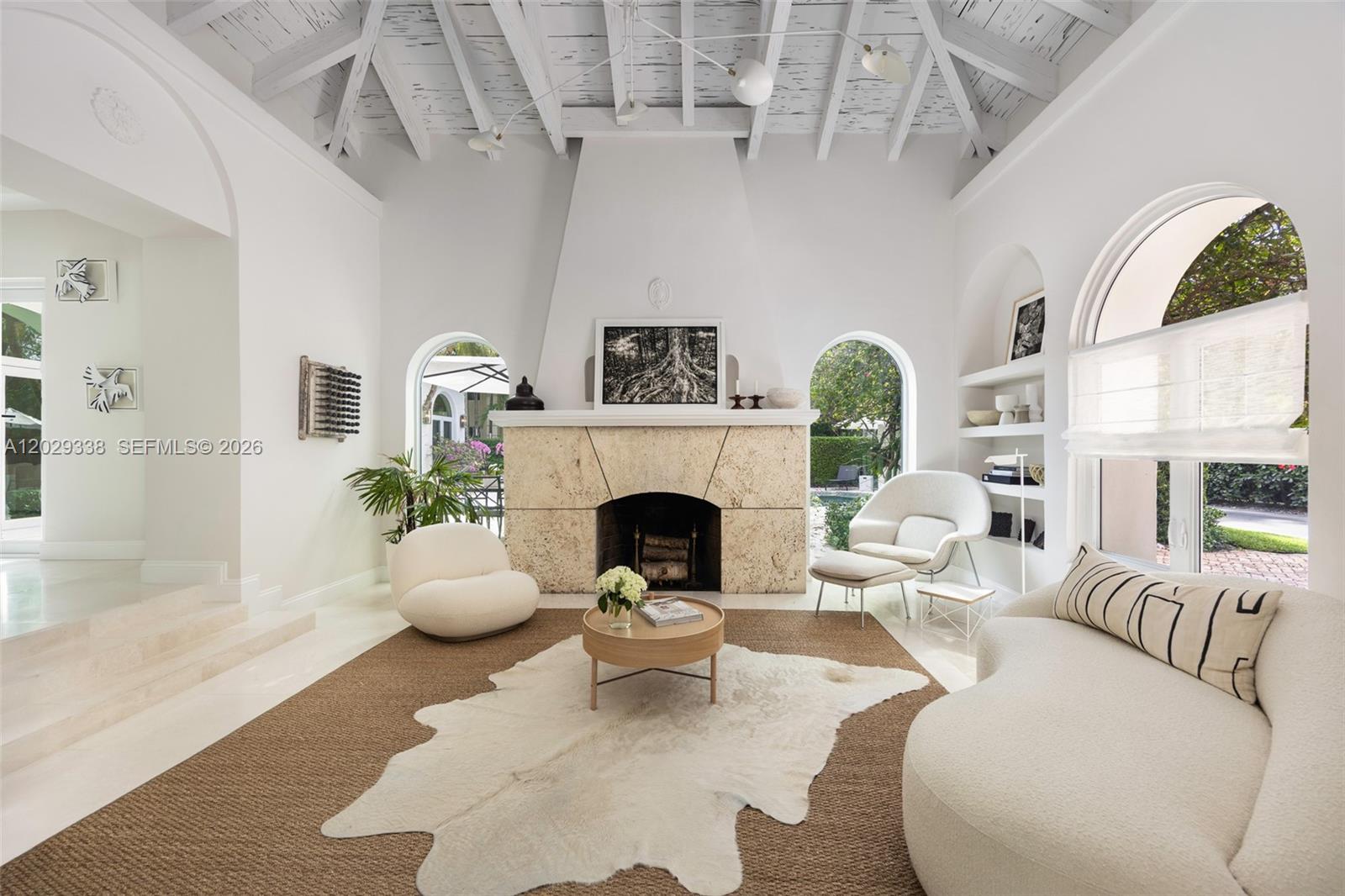 A bright living room features a stone fireplace, vaulted ceiling, and white curved furniture — 3845 Wood Ave, Miami FL 33133, MIAMI, FL