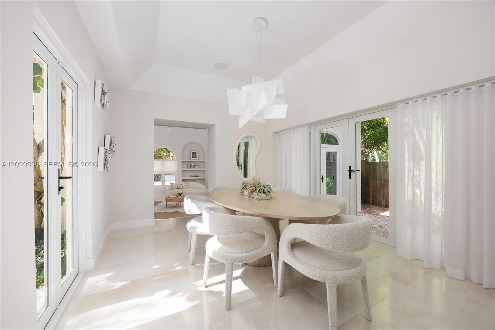 A dining room features a light wood oval table, textured chairs, and glass patio doors — 3845 Wood Ave, Miami FL 33133, MIAMI, FL