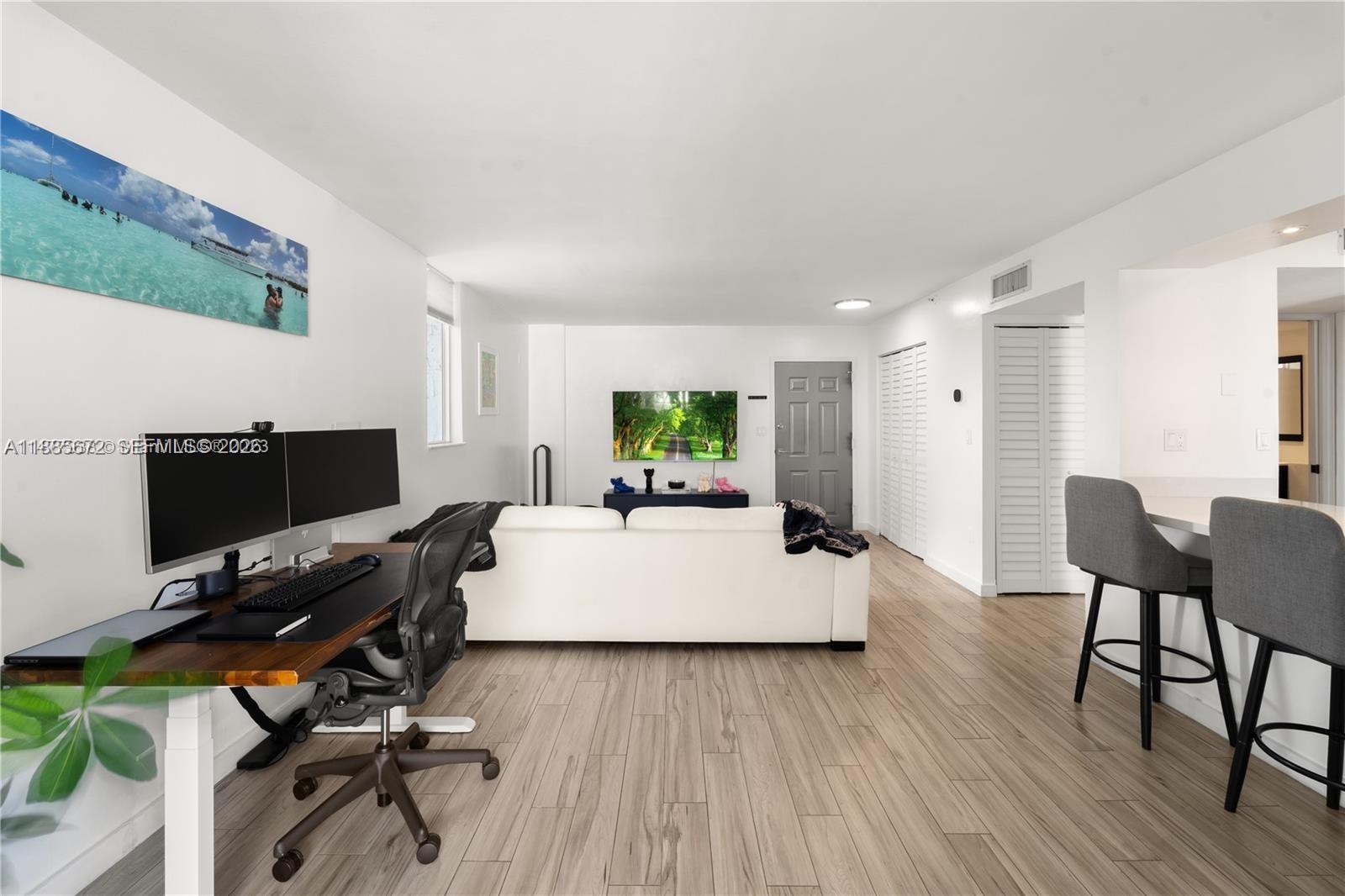 A living room features a desk, white sofa, television, and breakfast bar with stools — 650 NE 64th St, Miami FL 33138, MIAMI, FL