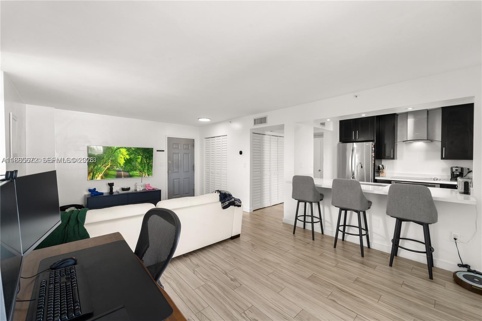 This open-concept living area features a kitchen with bar seating and light wood flooring — 650 NE 64th St, Miami FL 33138, MIAMI, FL