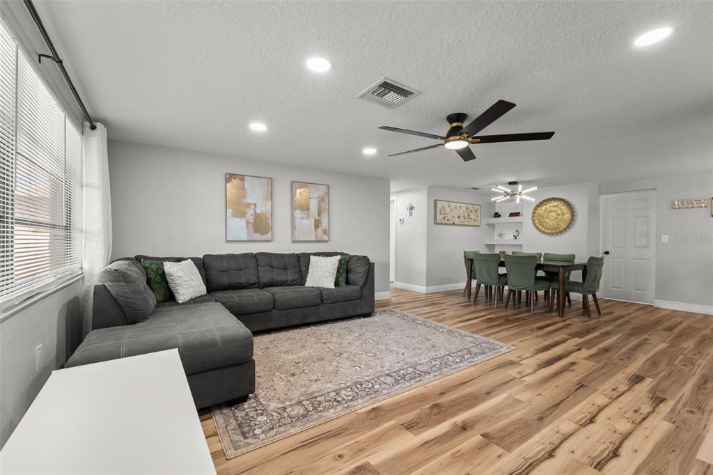 A living room with a gray sectional sofa, area rug, and an adjacent dining area — 6113 9TH AVENUE, NEW PORT RICHEY, FL