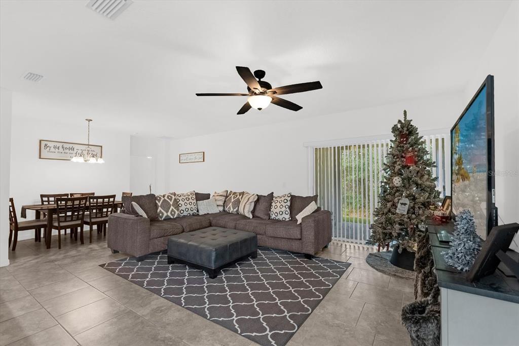 A living room with a sectional sofa, a Christmas tree, and an adjacent dining area — 34625 SALERNO CIRCLE, SORRENTO, FL