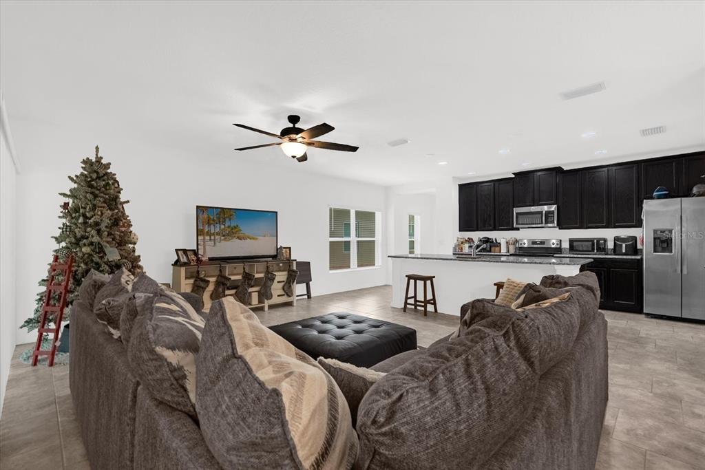 A living room with a sectional sofa, television, Christmas tree, and an open-concept kitchen — 34625 SALERNO CIRCLE, SORRENTO, FL