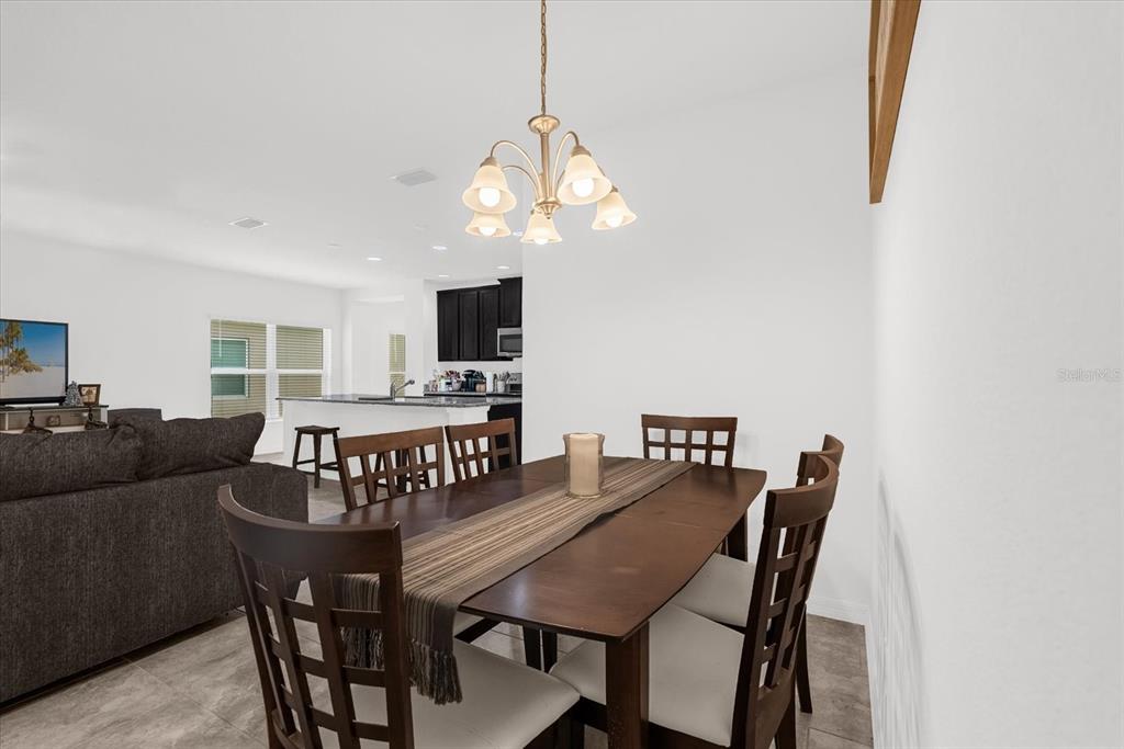 A dining area with a dark wood table and chairs sits beneath a chandelier — 34625 SALERNO CIRCLE, SORRENTO, FL