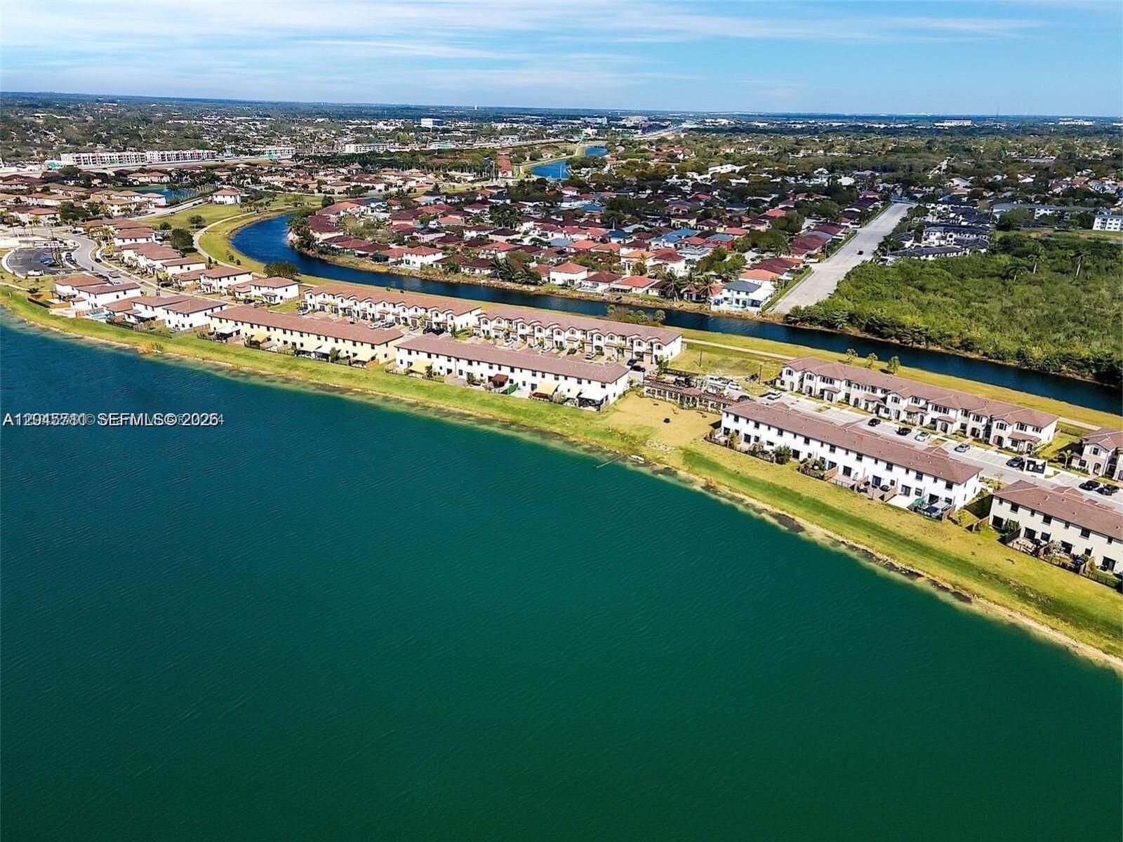 An aerial view shows townhouses situated along a large lake and a winding canal — 10100 SW 228 Terrace, Miami FL 33190, MIAMI, FL
