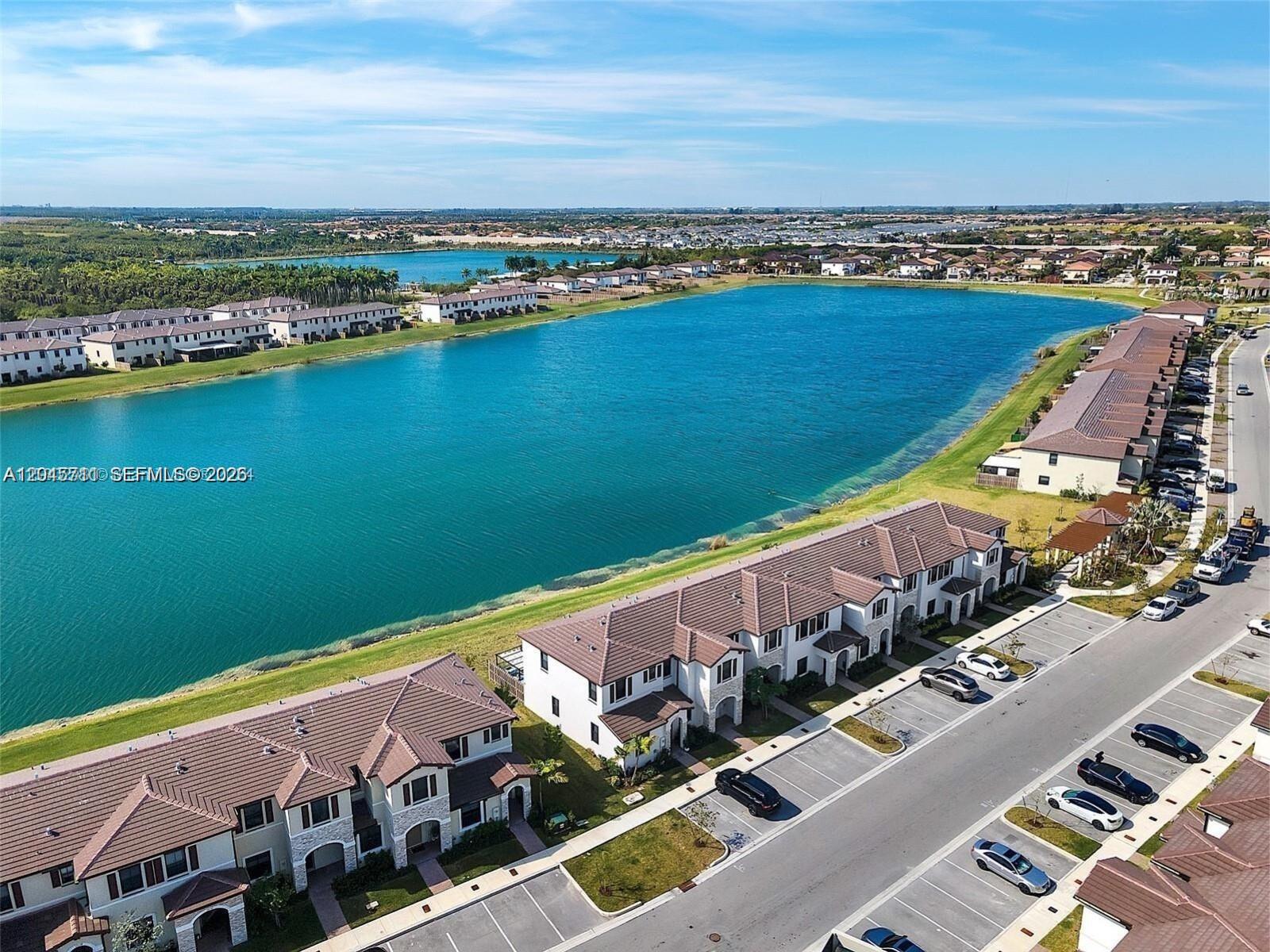 An aerial view shows townhouses situated along a large lake in a residential neighborhood — 10100 SW 228 Terrace, Miami FL 33190, MIAMI, FL