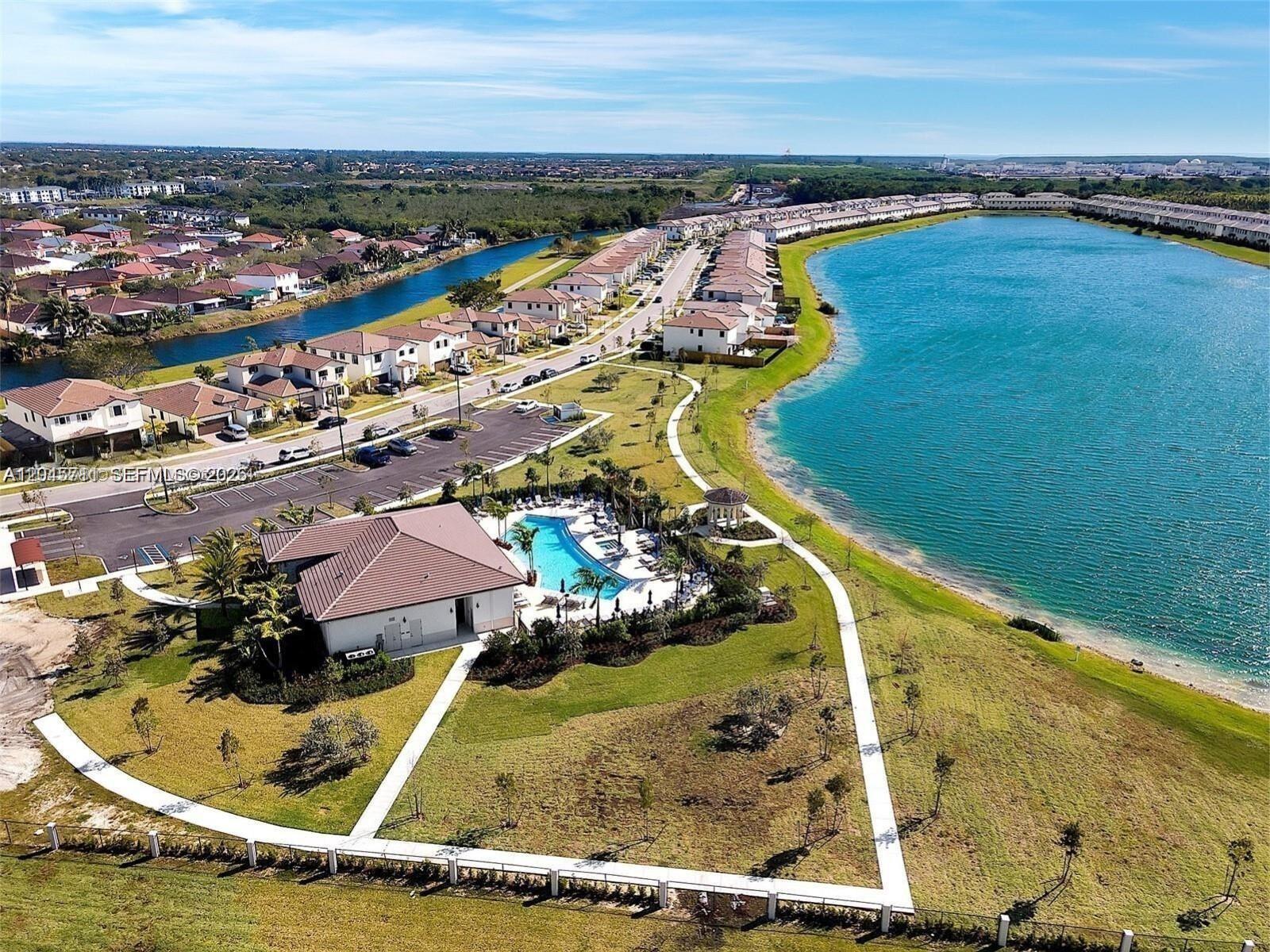 Aerial view of a residential community featuring a clubhouse, swimming pool, and a large lake — 10100 SW 228 Terrace, Miami FL 33190, MIAMI, FL