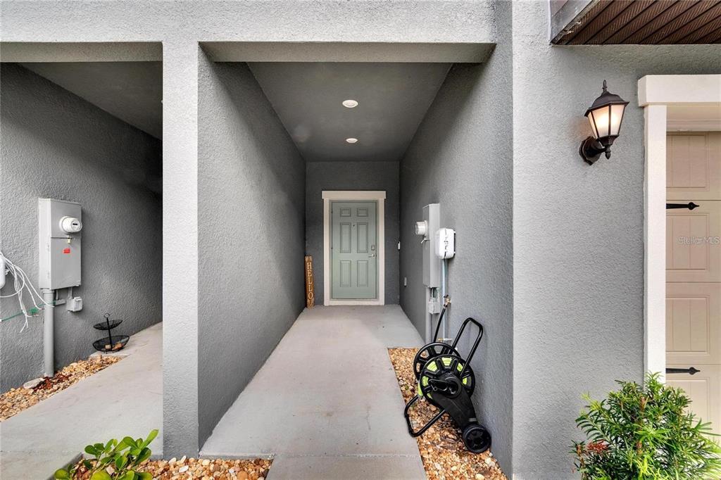 A gray stucco entryway features a light green front door and a garden hose reel — 14444 EDITORS NOTE STREET, SUN CITY CENTER, FL