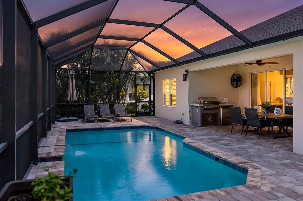 A kitchen features white cabinets, a gray island with bar seating, and wood-look tile flooring — 1215 THORNBURY DRIVE, PARRISH, FL
