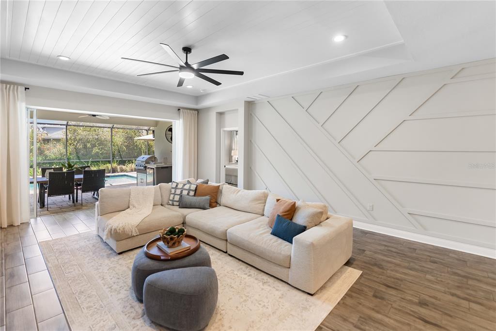 A bright living room features a large sectional sofa, a television, and sliding doors to a pool — 1215 THORNBURY DRIVE, PARRISH, FL