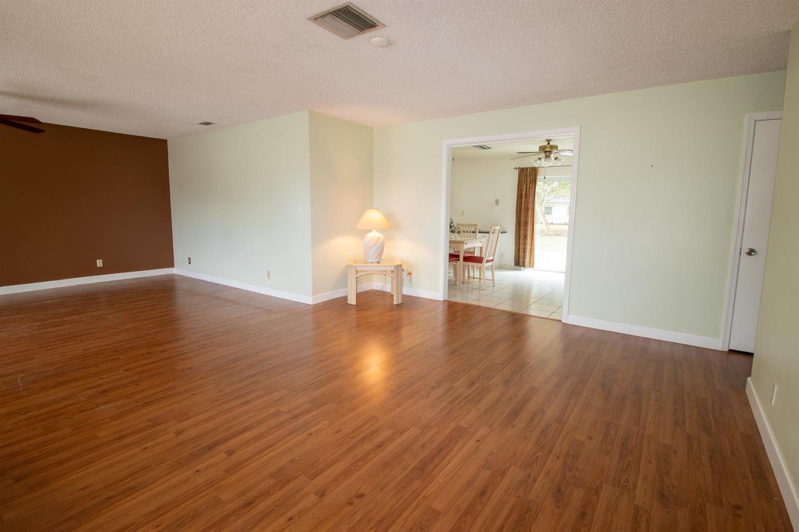 A spacious living room features wood-look flooring, light green walls, and a brown accent wall — 6860 Broadmoor, North Lauderdale FL 33068, NORTH LAUDERDALE, FL