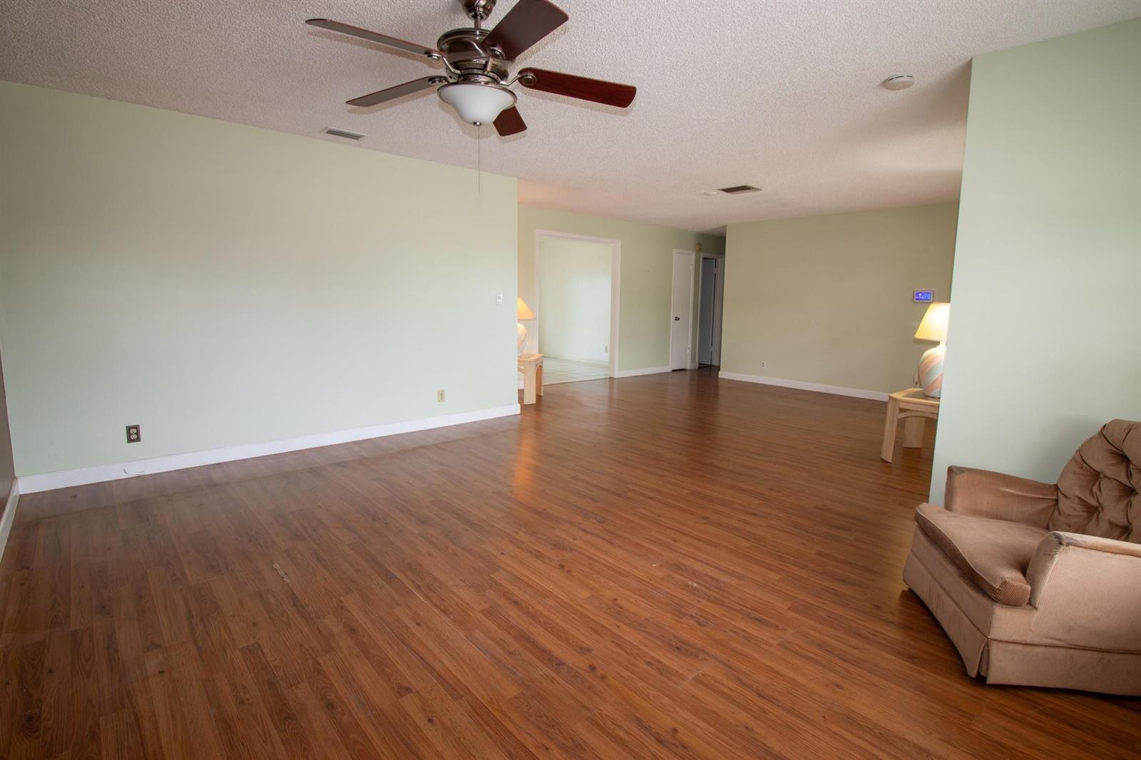 A spacious living room features light green walls, wood-look flooring, and a ceiling fan — 6860 Broadmoor, North Lauderdale FL 33068, NORTH LAUDERDALE, FL