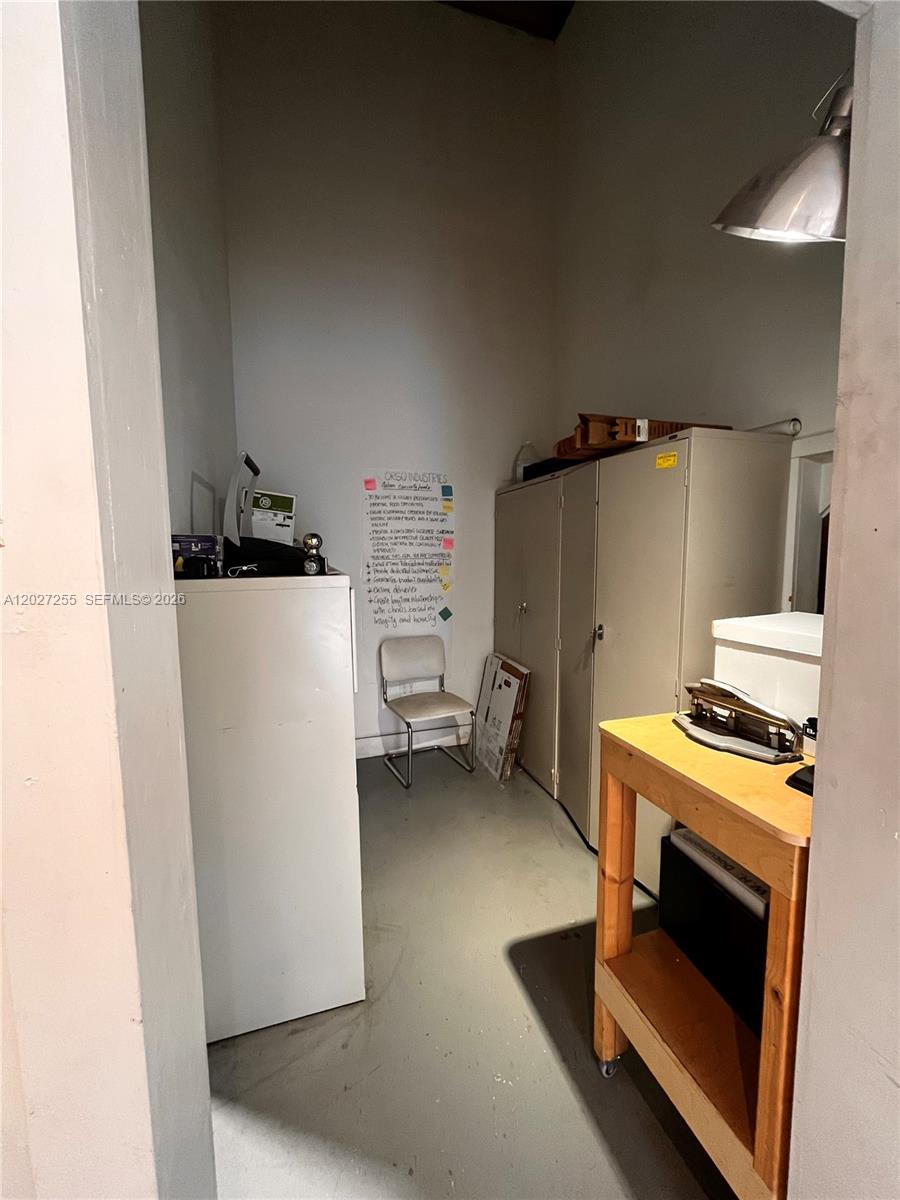 A small, utilitarian storage room features metal cabinets, a wooden work table, and a white chair — 8420 NW 61st St, Miami FL 33166, MIAMI, FL