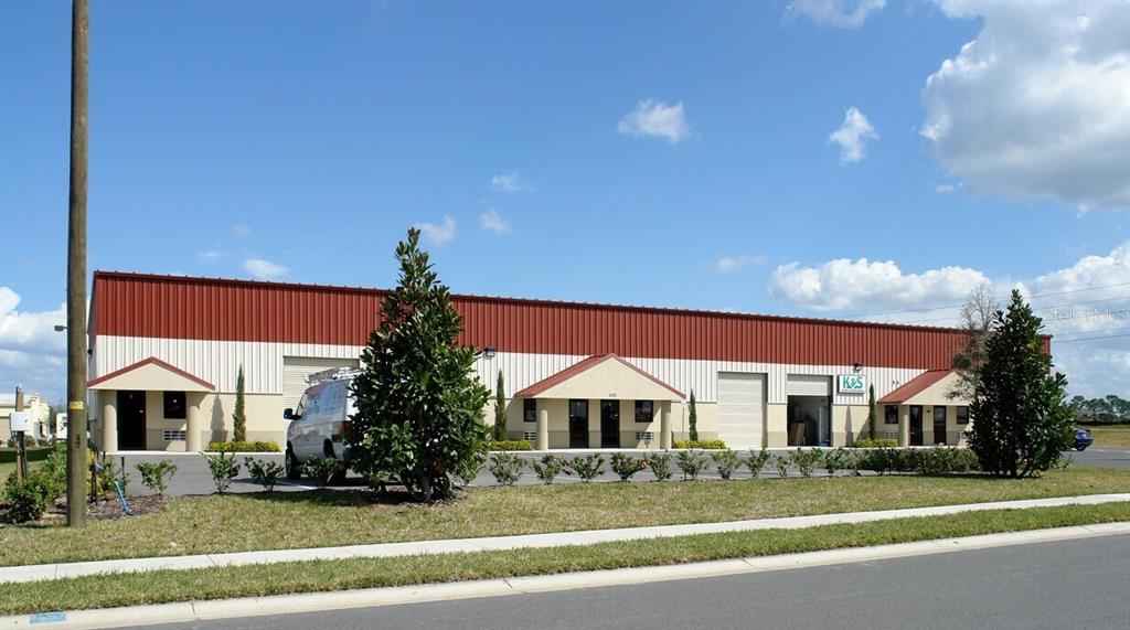 A single-story commercial building with a red metal roof and multiple entrance doors — 1805 GREENLEAF LANE, LEESBURG, FL