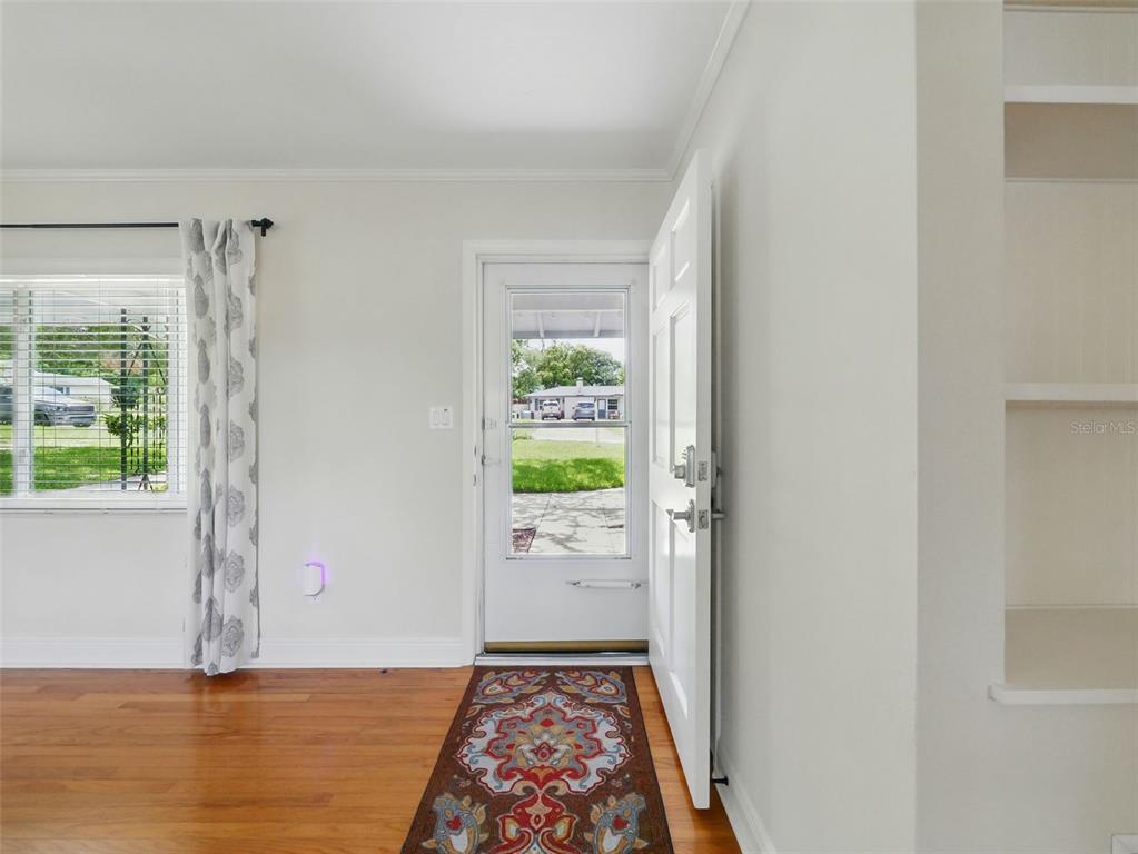 An entryway with hardwood floors, a white front door, and a window with patterned curtains — 1426 CRESTVIEW DRIVE, MOUNT DORA, FL