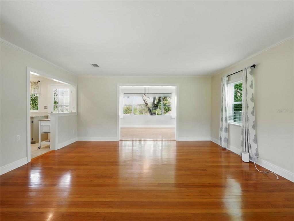 A bright living room features polished hardwood floors, neutral walls, and views into adjacent rooms — 1426 CRESTVIEW DRIVE, MOUNT DORA, FL
