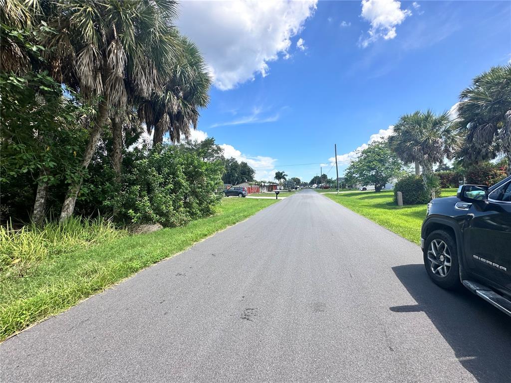 A paved road runs in front of a vacant lot with several tall palm trees — 18394 GOODMAN CIRCLE, PORT CHARLOTTE, FL