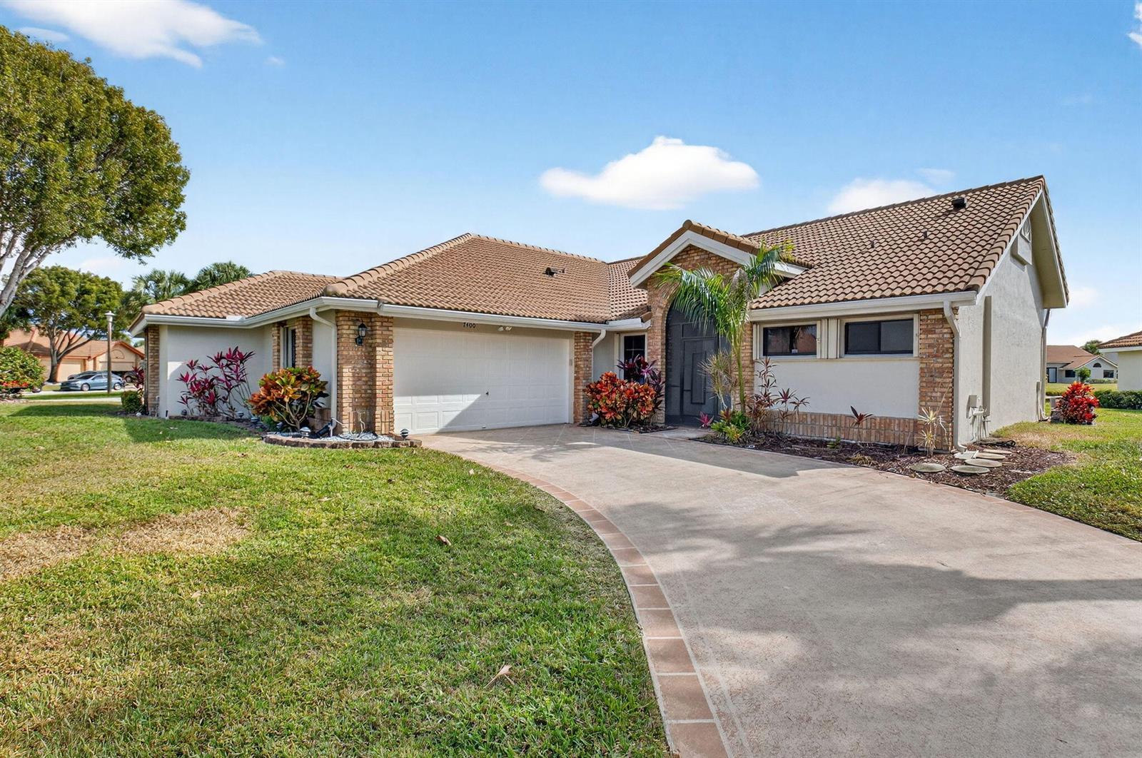 A single-story house with a tiled roof, brick accents, and a curved concrete driveway — 7400 Hearth Stone Avenue, Boynton Beach FL 33472, BOYNTON BEACH, FL