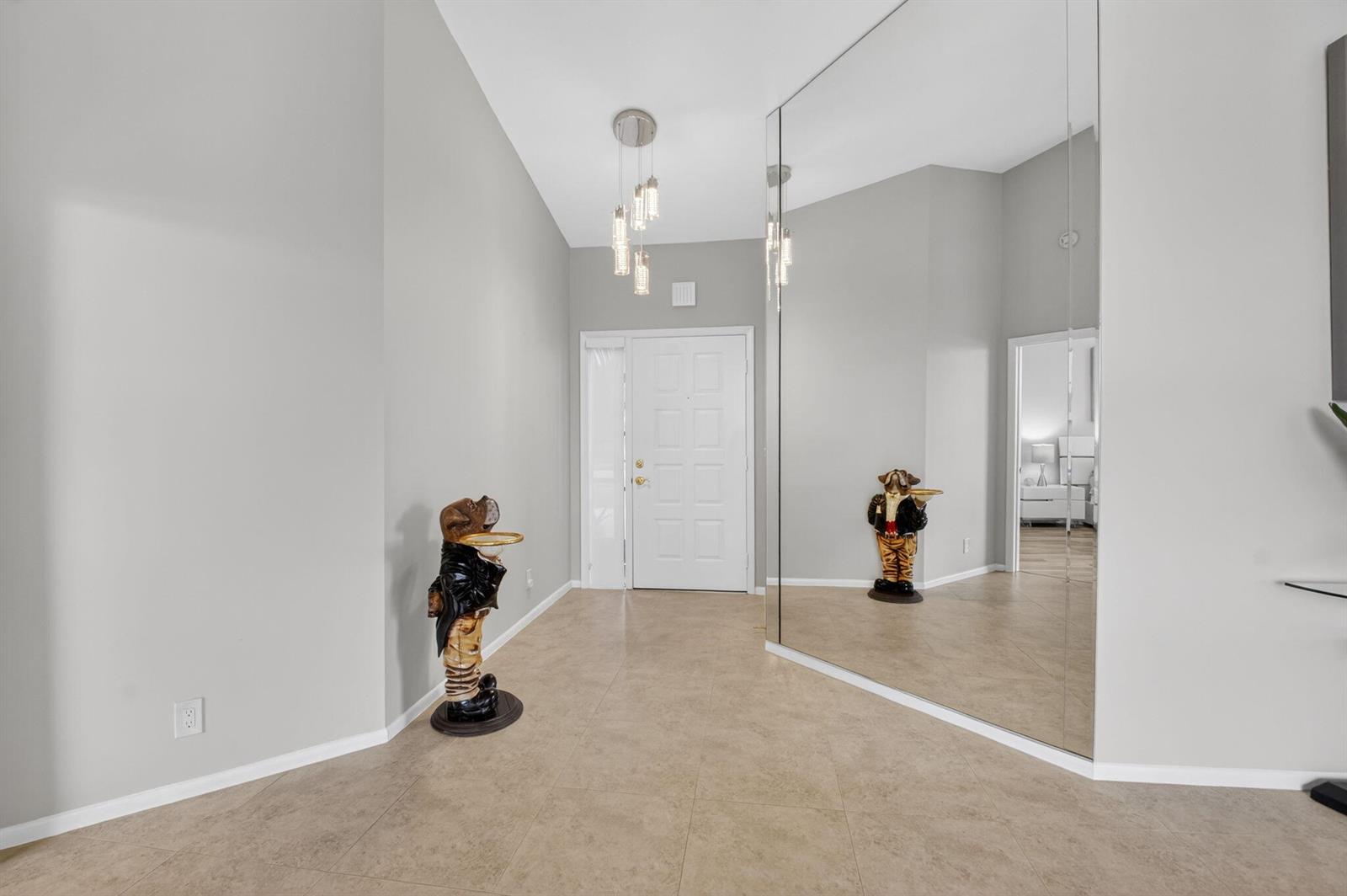 A foyer features light tile flooring, a white front door, a modern pendant light, and mirrors — 7400 Hearth Stone Avenue, Boynton Beach FL 33472, BOYNTON BEACH, FL
