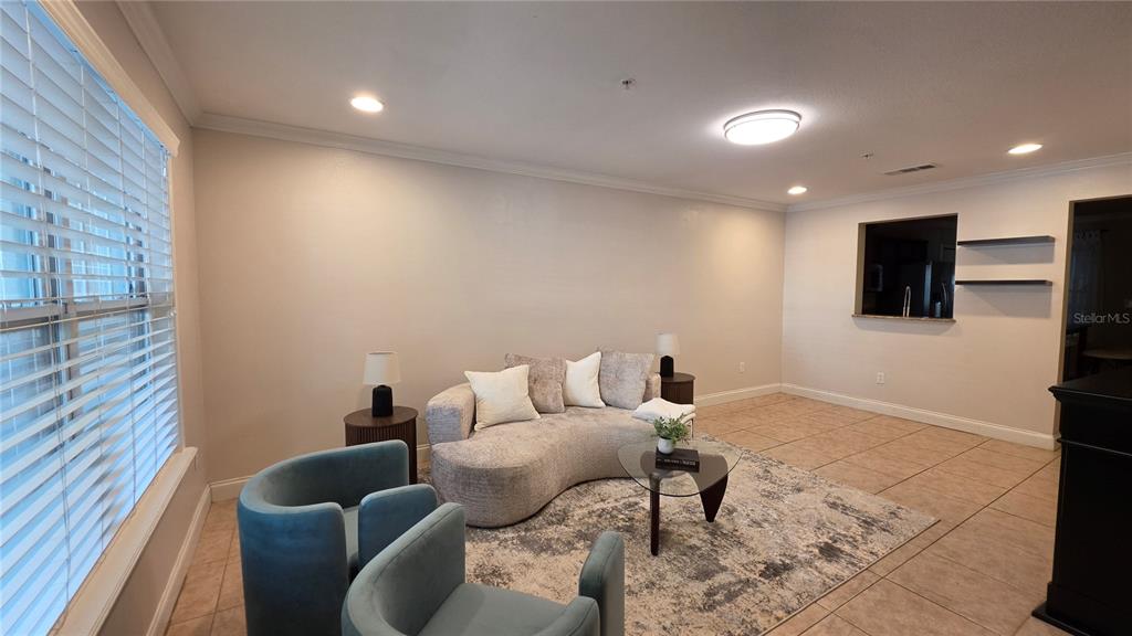 A living room features a curved sofa, two blue chairs, and tile flooring — 4639 SW 48TH DRIVE UNIT 151, GAINESVILLE, FL