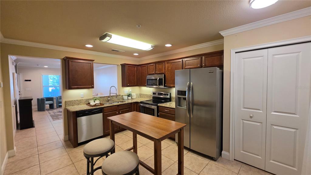 A kitchen features dark wood cabinets, stainless steel appliances, granite countertops, and a wooden island — 4639 SW 48TH DRIVE UNIT 151, GAINESVILLE, FL