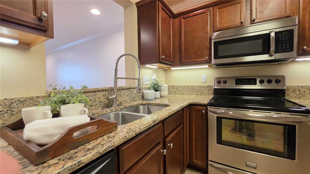 A kitchen features dark wood cabinets, granite countertops, stainless steel appliances, and a double sink — 4639 SW 48TH DRIVE UNIT 151, GAINESVILLE, FL